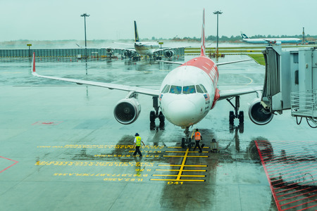 Singapore - August 12, 2017: Changi Airport Jetway for boarding passengers attached to the airplane in the raining day, an airplane stationary at airport passengers boarding to the planeのeditorial素材