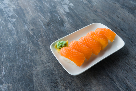 Fresh Japanese Salmon Sushi in white dish with Wasabi and gingers on wood table with copy spaceの写真素材
