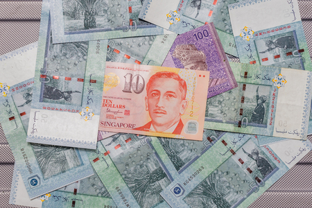 Singapore dollar on top of Malaysian Ringgit currency on pattern background, symbol RM currency code...
