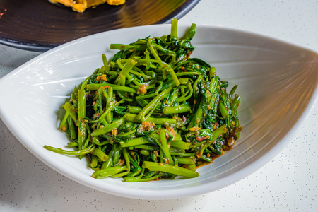 Chinese Fried Water Spinach with spicy chili garlic and soy sauce on white plate, in Singapore called Sambal Kangkongの写真素材