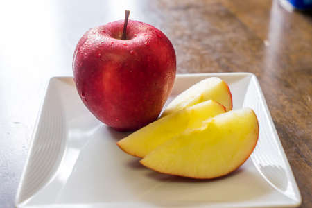 Red apple on a white square plate, Sliced fresh red apple on a white dish