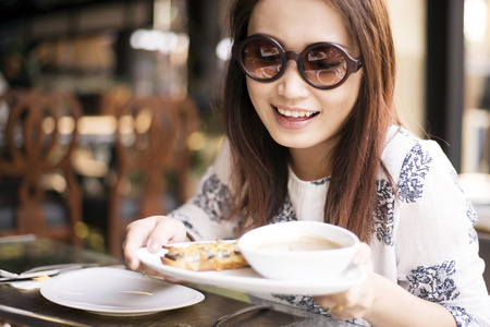 Happy young women eating mushroom cream soup and oyster cheese breadの写真素材