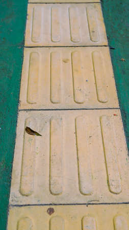 Pedestrian walking on tactile paving on footpath in selective focusの写真素材