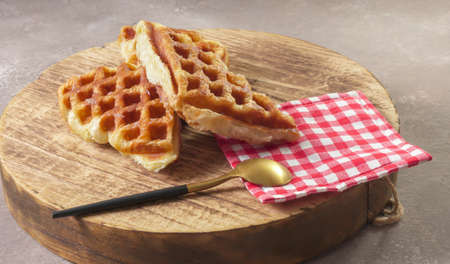 Jakarta 11th November 2021, Asian cute girl biting Stack of Croissant Waffle or Croffle served in round wood surface plate. Selective focus image.の写真素材