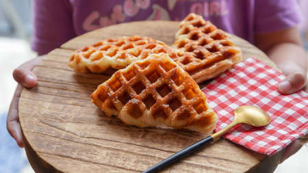 Stack of Croissant Waffle or Croffle served in round wood surface plate. Selective focus image.の写真素材