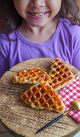 Stack of Croissant Waffle or Croffle served in round wood surface plate. Selective focus image.の写真素材