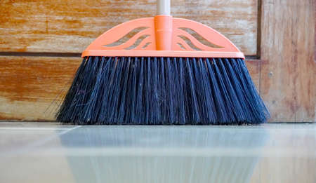 Kit of the yellow plastic broom with gray bristles for sweeping floors and dustpan on a white background, working parts close-up in selective focusの写真素材