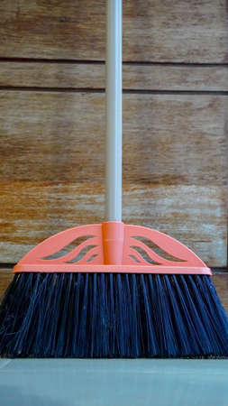 Kit of the yellow plastic broom with gray bristles for sweeping floors and dustpan on a white background, working parts close-up in selective focusの写真素材