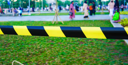 Black and yellow warning tape on green grass background. Selective focus.の写真素材
