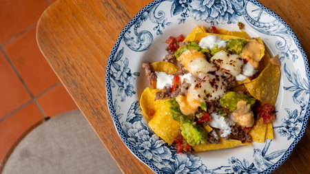 Corn chips nachos with fried minced meat and guacamole on wooden background.の写真素材