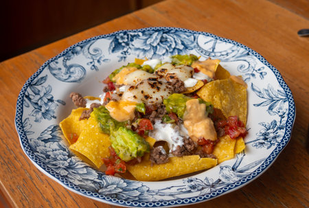 Corn chips nachos with fried minced meat and guacamole on wooden background.の写真素材