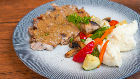 Pork chop with mashed potatoes and vegetables on wooden table, Thailand.の写真素材