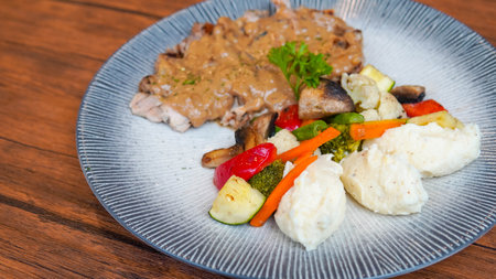 steak with mashed potatoes and vegetables in a plate on a wooden tableの写真素材