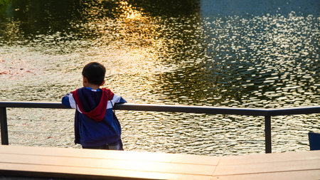 Little boy playing on the lake in the park at sunset time.