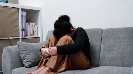 sad woman sitting on sofa and crying in living room at home