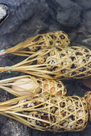 Quail eggs in round bamboo basket boil on hot springの写真素材