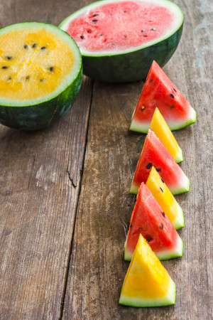 sweet red and yellow watermelons ion wood table.の写真素材