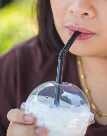 young woman drinking ice coffeeの写真素材