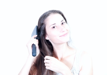 Young beautiful brown-haired woman is combing her hairの写真素材