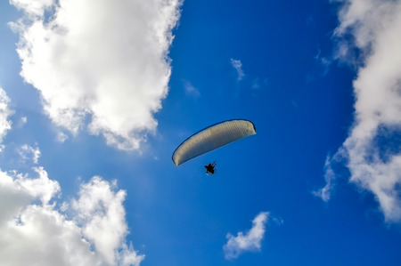 Paraglider flying in the cloudy blue skyの写真素材