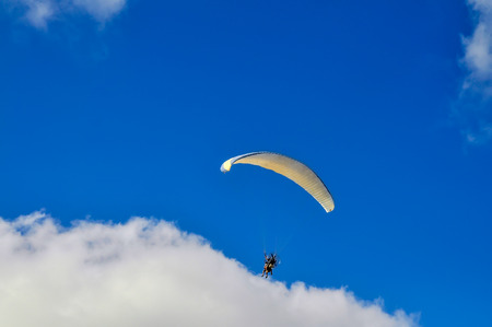 View on flying paragliding in the cloudy blue sky