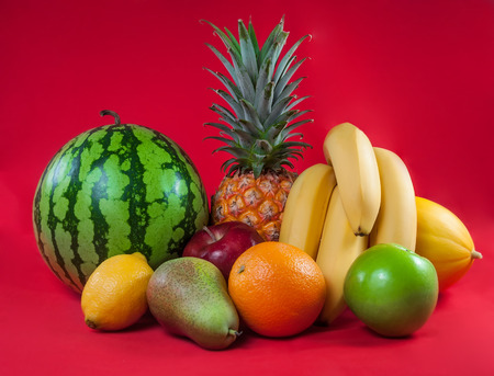 Fresh ripe tropical fruits on red backgroundの写真素材