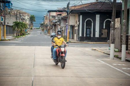 A people riding a scooter on a city streetのeditorial素材