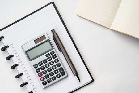 Top view of white table with notebook, calculator and penの写真素材