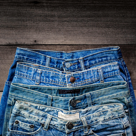 Blue jean and jean lack texture on the wooden floor, Pattern of blue jeans are overlapping on the table and free space.の写真素材