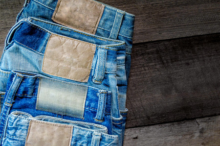 Blue jean and jean lack texture on the wooden floor, Pattern of blue jeans are overlapping on the table.の写真素材