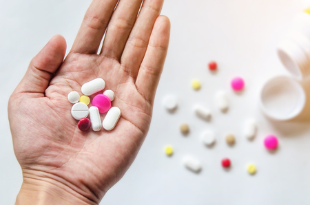 Top view of the pills on the hand and white background, A hand hold the pills and drug, Pile of the drug and pills on the hand.の写真素材