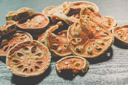 Dried herbs and dried bael fruit, Close-up of bael dry on the wooden floor, Many of slices of bael fruit for make bael juice on the dark table.の写真素材