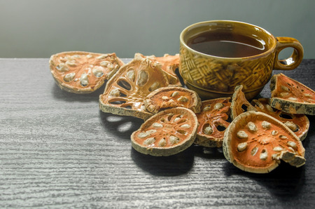 Dried herbs and dried bael fruit, Close-up of bael dry and glass tea and bael juice on the wooden floor, Slices of bael fruit on the dark table.の写真素材