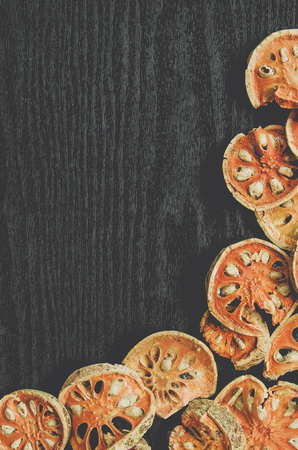 Dried herbs and dried bael fruit, Top view of bael dry on the wooden floor, Slices of bael fruit for...