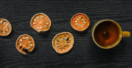 Dried herbs and dried bael fruit, Top view of bael dry and glass tea and bael juice on the wooden floor, Slices of bael fruit on the dark table.の写真素材