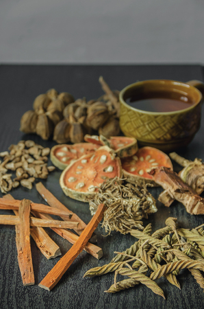 Dried herbs and Ginseng, Close-up of Thai herbs and ginseng on wooden floor. Slices of dries root for make a herb juice on the dark table.の写真素材