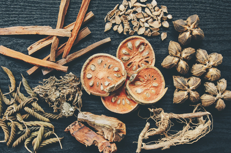 Dried herbs and Ginseng, Close-up of Thai herbs and ginseng on wooden floor. Slices of dries root for make a herb juice on the dark table.の写真素材