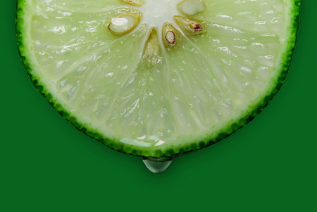 Close up of green lemon or lime on the green background, Fresh lemon(lime) slice and sour fruit or...