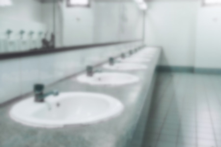 Blurry background of public toilet and bathroom interior with white wash basin and sink or lavatory, Blurry of the wash bowl and basin with the stain dirty in the toilet.の写真素材