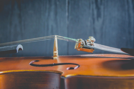 The violin on the dark table, Close - up of violin on the wooden floor, Top view of violin musical on dark wooden floor, Vintage and classic musical instrument used in the orchestra.の写真素材