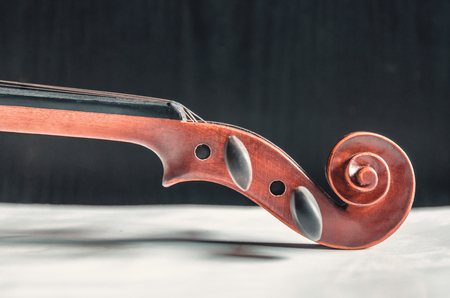 The violin on the dark table, Close - up of violin on the wooden floor, Top view of violin musical on dark wooden floor, Vintage and classic musical instrument used in the orchestra.の写真素材