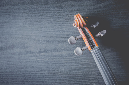 The violin on the dark table, Close - up of violin on the wooden floor, Top view of violin musical on dark wooden floor, Vintage and classic musical instrument used in the orchestra.の写真素材