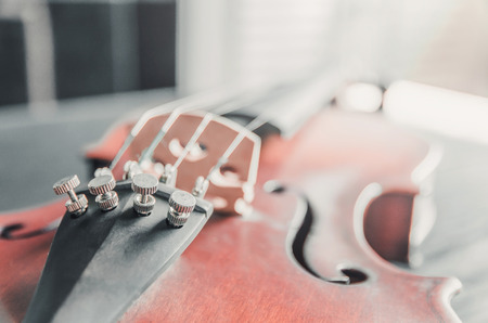 The violin on the dark table, Close - up of violin on the wooden floor, Top view of violin musical on dark wooden floor, Vintage and classic musical instrument used in the orchestra.の写真素材