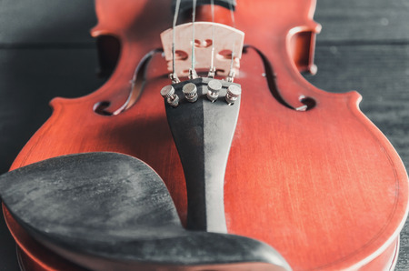 The violin on the dark table, Close - up of violin on the wooden floor, Top view of violin musical on dark wooden floor, Vintage and classic musical instrument used in the orchestra.の写真素材