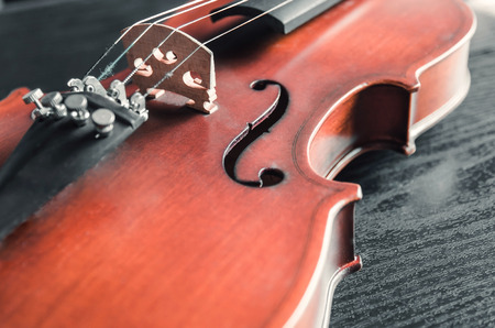 The violin on the dark table, Close - up of violin on the wooden floor, Top view of violin musical on dark wooden floor, Vintage and classic musical instrument used in the orchestra.の写真素材