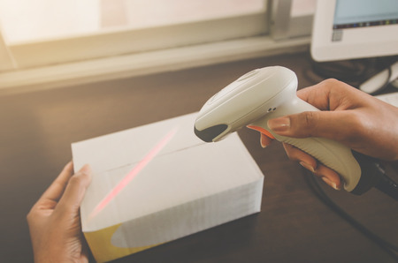 A parcel box and hand holding a package with barcode reader, Delivery concept and shipping of parcel, mail and box, A human hand holding mail box for delivery, Prepare parcel or package for shipping.の写真素材