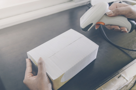 A parcel box and hand holding a package with barcode reader, Delivery concept and shipping of parcel, mail and box, A human hand holding mail box for delivery, Prepare parcel or package for shipping.の写真素材