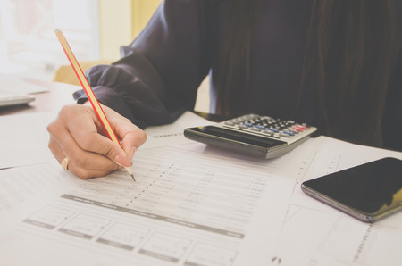Business concept of financial and accounting with human hand are pointing on paper sheet and writing, Finance report and with paper sheet of planning data and analyze graph and chart on the table.の写真素材