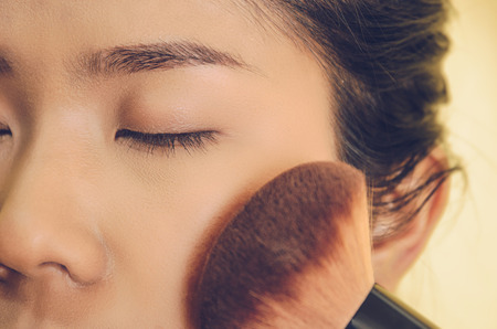 Beauty face of Asian woman by applying brushes, The girl is makeup her face with brush on, Soft and smooth face skin by cosmetics and foundation and using makeup brush on the face.の写真素材