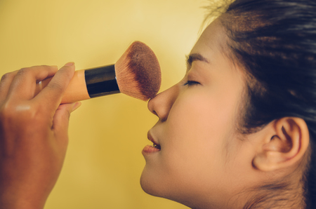Beauty face of Asian woman by applying brushes, The girl is makeup her face with brush on, Soft and smooth face skin by cosmetics and foundation and using makeup brush on the face.の写真素材